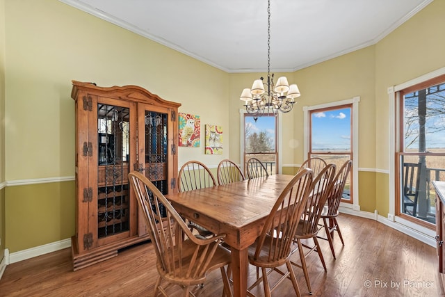 dining area featuring a chandelier, baseboards, wood finished floors, and ornamental molding