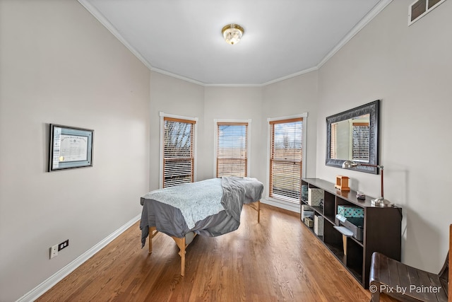 bedroom with visible vents, wood finished floors, baseboards, and ornamental molding