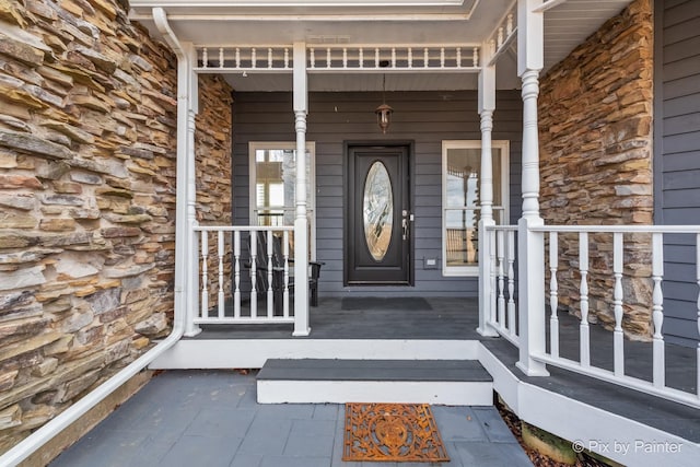 doorway to property with stone siding and a porch