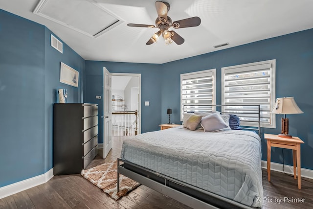 bedroom featuring attic access, wood finished floors, visible vents, and baseboards