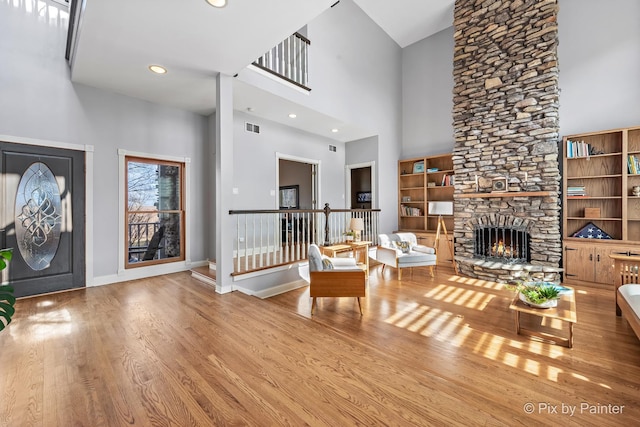 entrance foyer featuring baseboards, a stone fireplace, wood finished floors, and a towering ceiling