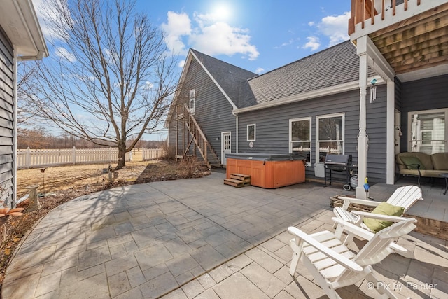 view of patio / terrace with a hot tub, stairs, and fence