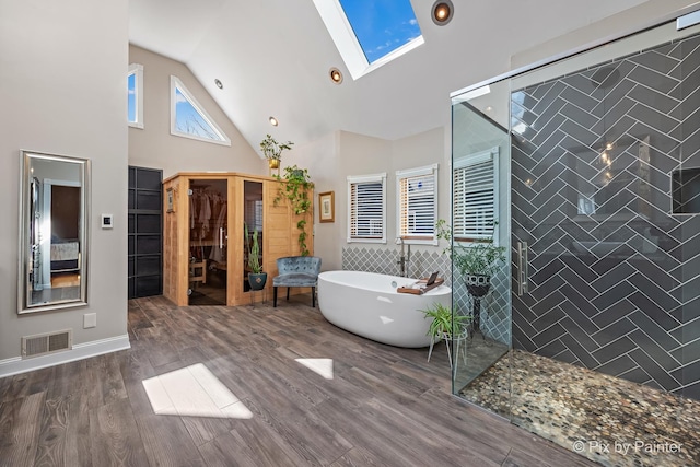 full bathroom with visible vents, tile walls, a skylight, tiled shower, and a soaking tub