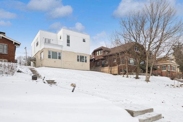 snow covered rear of property with stucco siding