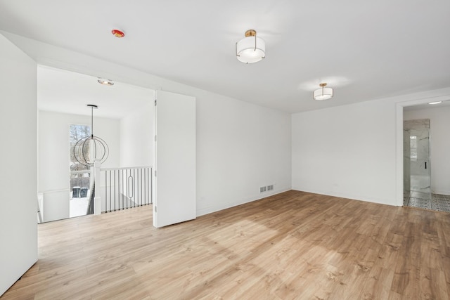 empty room featuring light wood-type flooring, visible vents, and baseboards