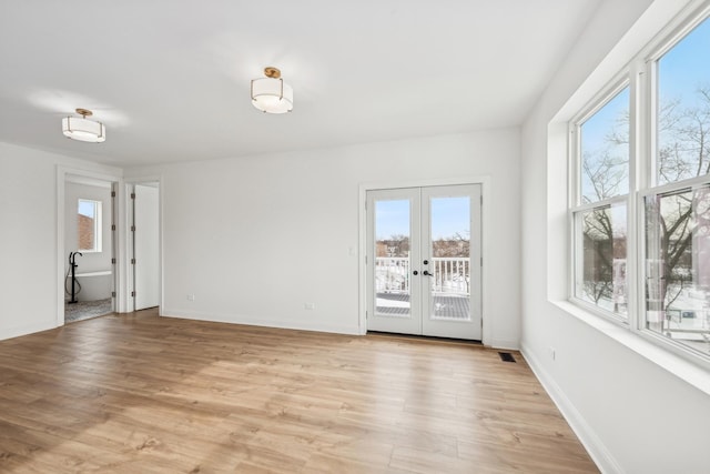 empty room featuring visible vents, french doors, light wood-style flooring, and baseboards