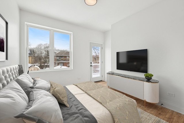 bedroom featuring access to outside, wood finished floors, and baseboards