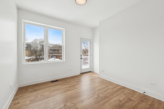 unfurnished room with light wood-type flooring, baseboards, and visible vents