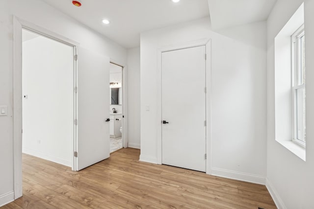 unfurnished bedroom with recessed lighting, multiple windows, light wood-style flooring, and baseboards