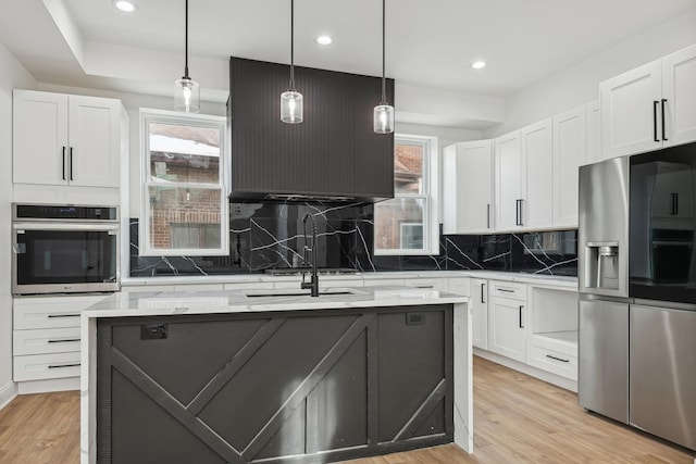 kitchen featuring appliances with stainless steel finishes, white cabinetry, light wood-style flooring, and a healthy amount of sunlight