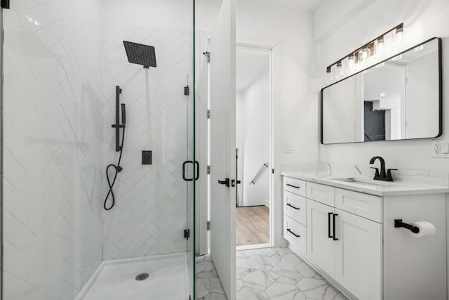 bathroom with marble finish floor, a shower stall, and vanity