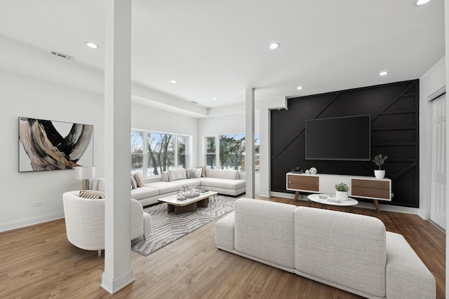 living area with recessed lighting, wood finished floors, visible vents, and baseboards