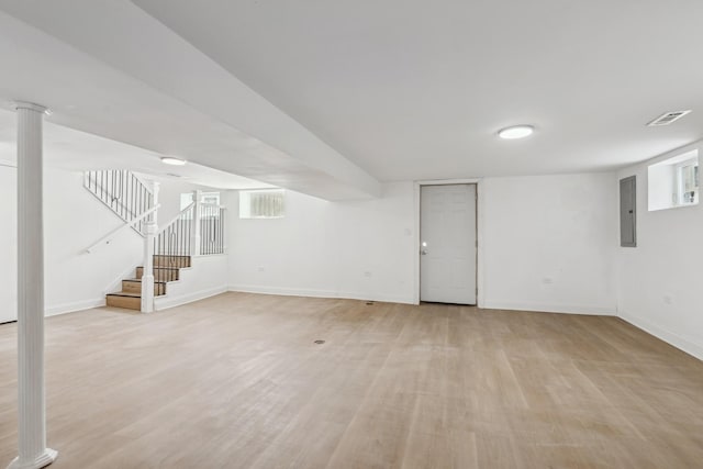 below grade area featuring light wood-style flooring, electric panel, stairway, and baseboards