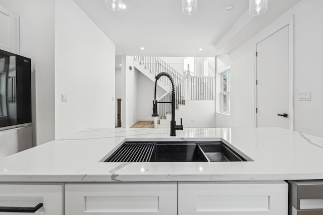 kitchen with white cabinets, a sink, smart refrigerator, and light stone countertops