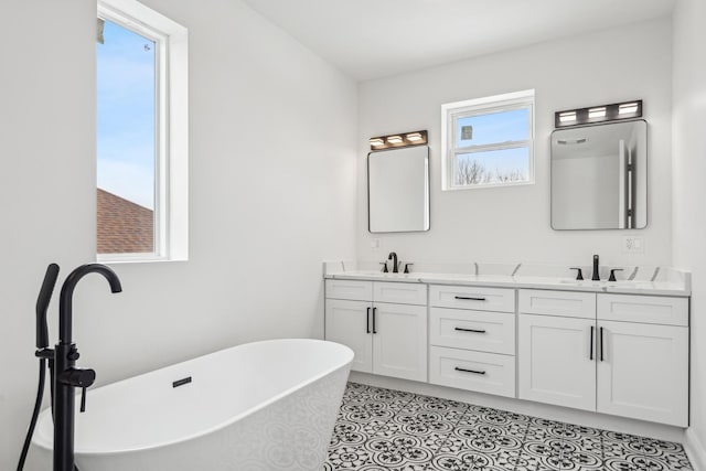 bathroom featuring tile patterned flooring, a sink, a freestanding bath, and double vanity