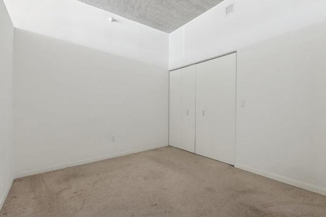 unfurnished bedroom with light carpet, a closet, visible vents, and baseboards