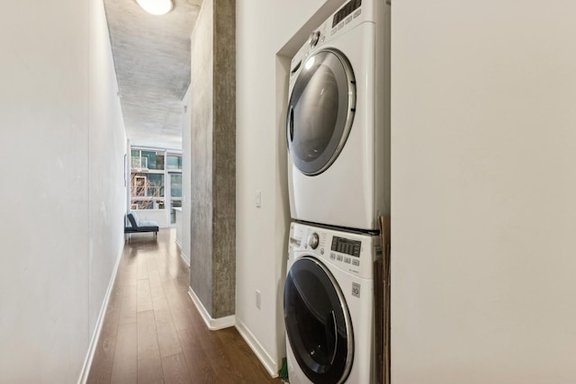 washroom with stacked washer and dryer, baseboards, laundry area, and dark wood-style floors