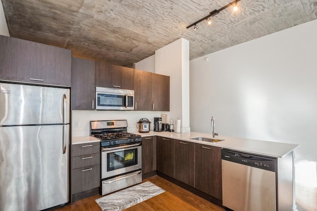 kitchen with a sink, dark wood-style floors, stainless steel appliances, and light countertops