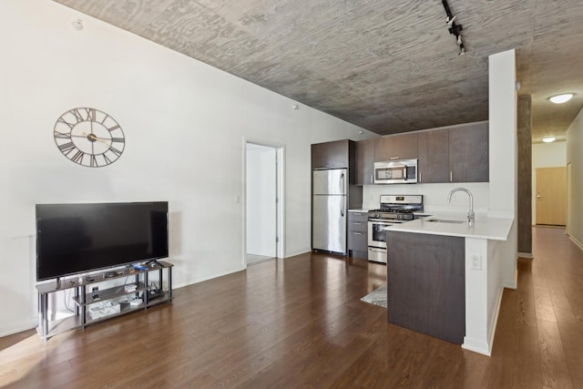 kitchen with dark wood-style floors, light countertops, appliances with stainless steel finishes, dark brown cabinetry, and a sink