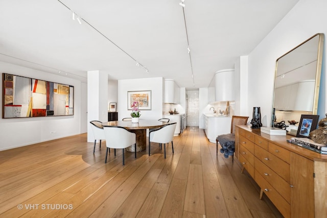 dining space with light wood-type flooring and rail lighting