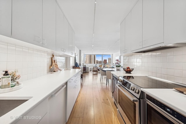 kitchen featuring stainless steel appliances, white cabinets, light countertops, and open floor plan