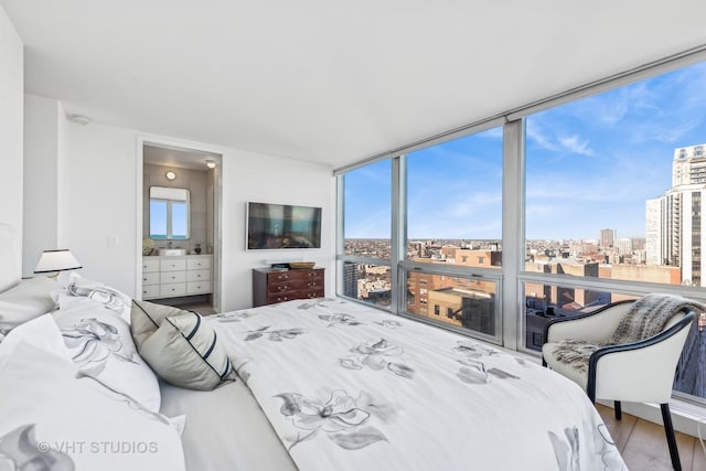 bedroom featuring ensuite bath, floor to ceiling windows, and wood finished floors