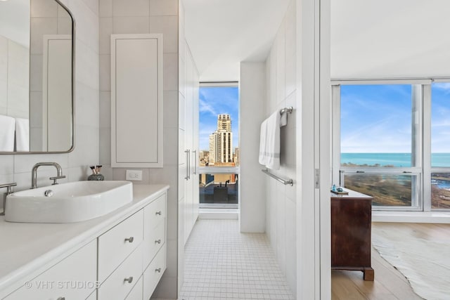 bathroom featuring a water view, expansive windows, tile walls, and vanity