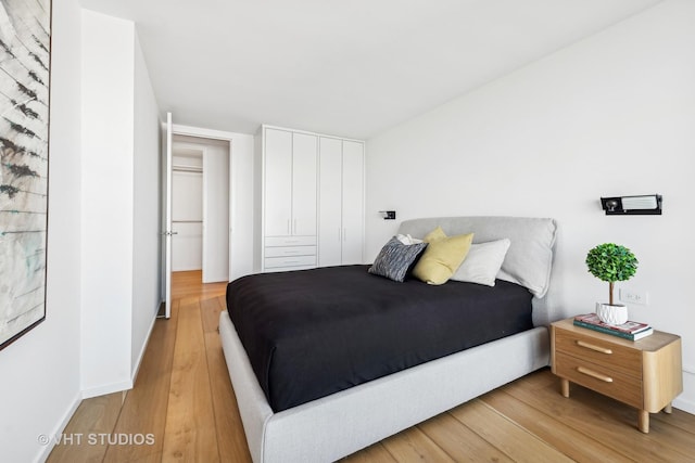 bedroom featuring light wood-type flooring, baseboards, and a closet