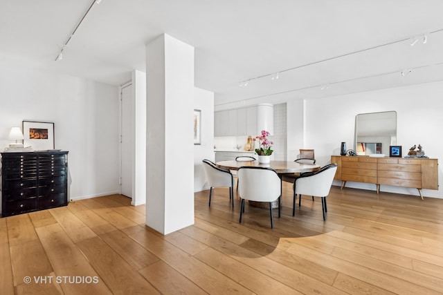 dining area with light wood finished floors and rail lighting