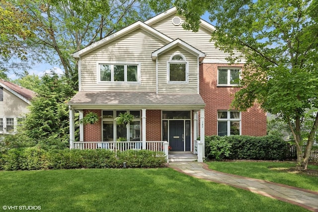 traditional-style house featuring covered porch, brick siding, roof with shingles, and a front yard