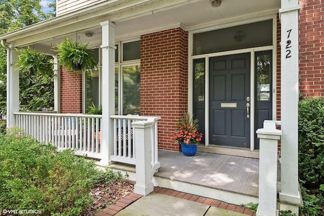 property entrance with covered porch and brick siding