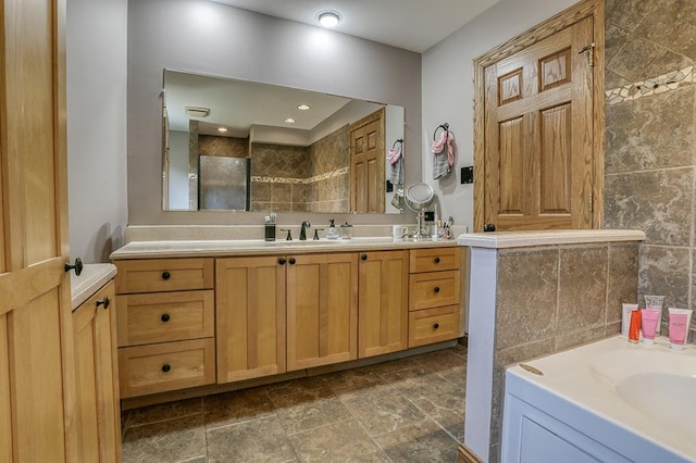 bathroom with a tile shower, vanity, stone finish floors, and tile walls