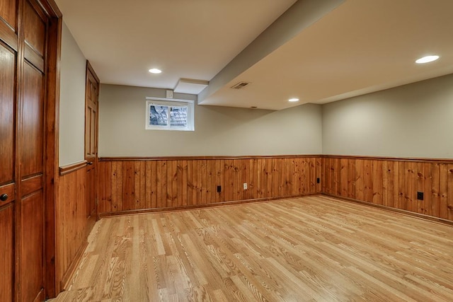below grade area featuring light wood-style floors, wainscoting, wooden walls, and recessed lighting