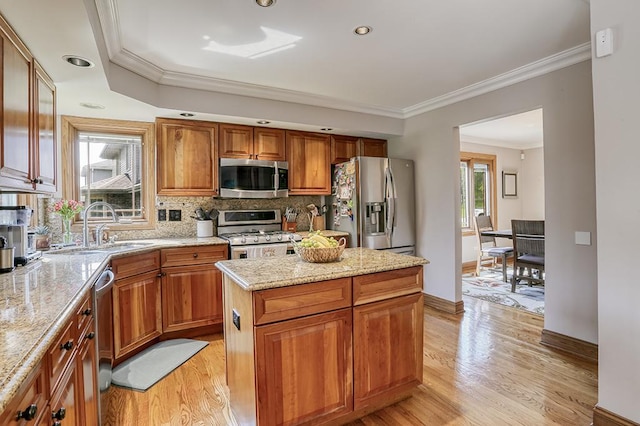kitchen with stainless steel appliances, a sink, decorative backsplash, a kitchen island, and brown cabinetry