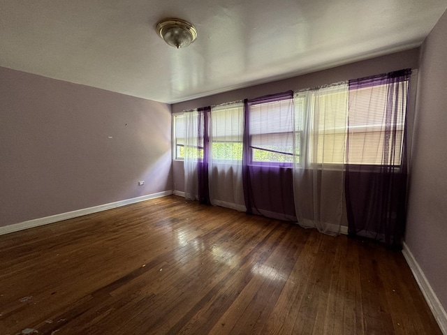 unfurnished room with dark wood-style flooring and baseboards