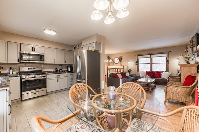 kitchen with a notable chandelier, stainless steel appliances, dark countertops, gray cabinetry, and open floor plan