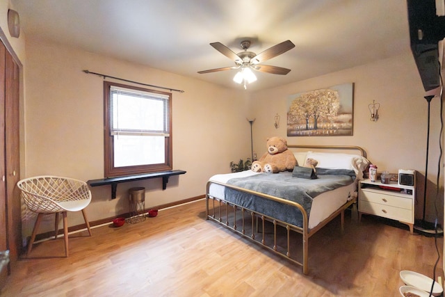 bedroom with a ceiling fan, wood finished floors, and baseboards