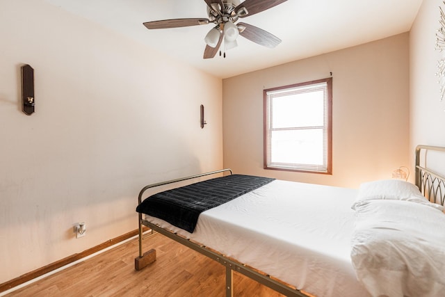 bedroom with baseboards, wood finished floors, and a ceiling fan