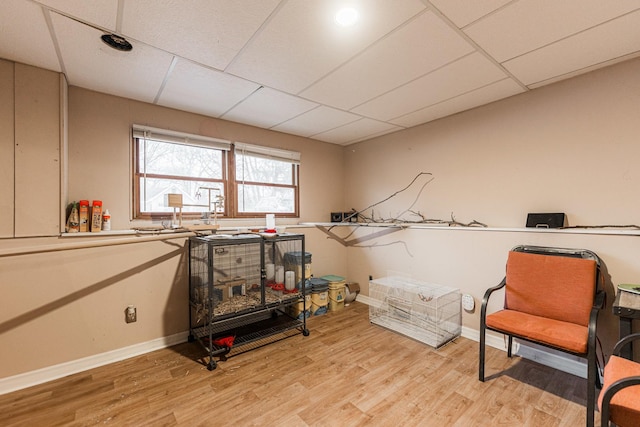 misc room with a paneled ceiling, baseboards, and light wood-style floors