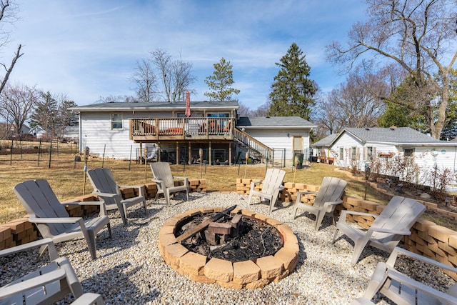 rear view of property featuring fence, stairway, a wooden deck, an outdoor fire pit, and a patio