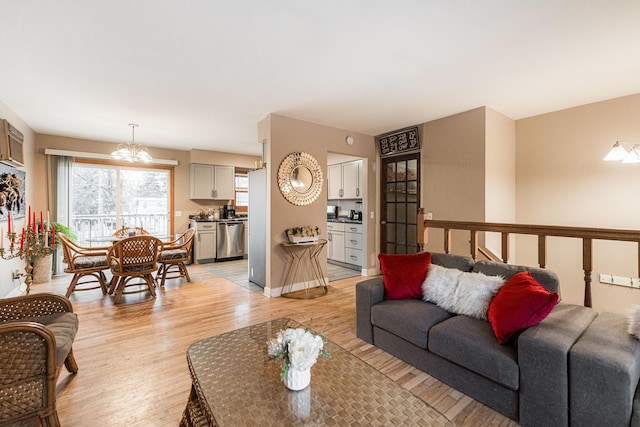 living room featuring an inviting chandelier, baseboards, and light wood finished floors