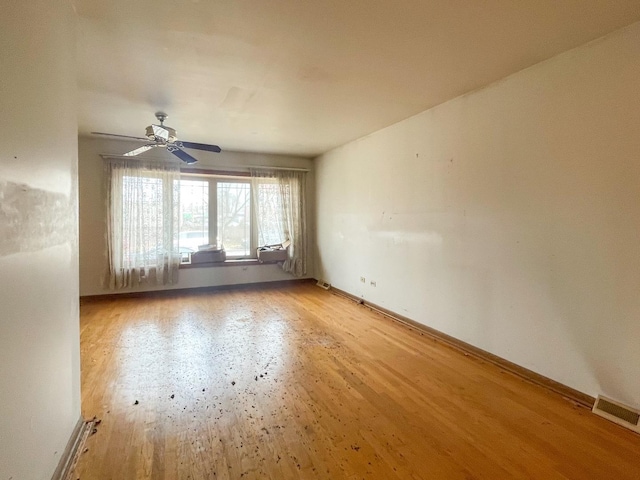 unfurnished room featuring light wood-style floors, baseboards, visible vents, and a ceiling fan