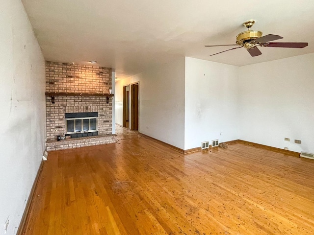 unfurnished living room with a fireplace, baseboards, and wood finished floors