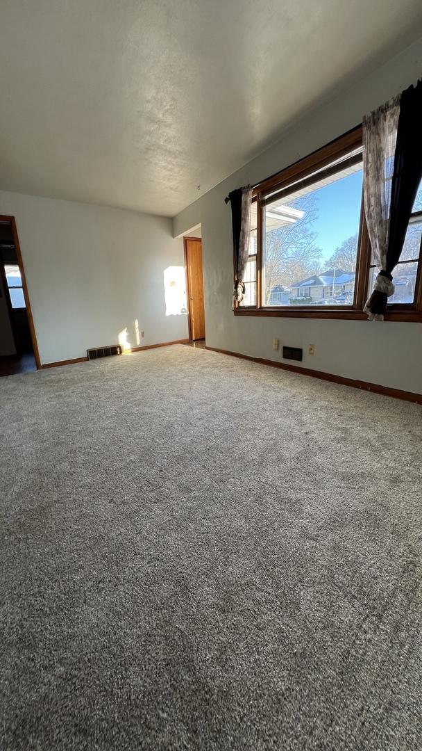 spare room featuring carpet floors, visible vents, and baseboards