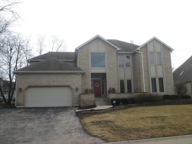 view of front facade with driveway, a shingled roof, an attached garage, and a front yard