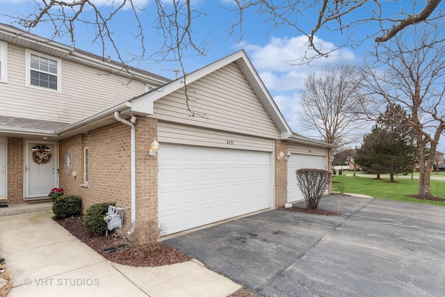 view of side of home with a garage, a yard, aphalt driveway, and brick siding