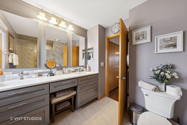 bathroom featuring tile patterned flooring, toilet, a sink, decorative backsplash, and double vanity