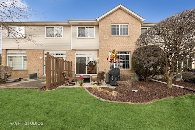 rear view of property featuring central air condition unit, brick siding, a lawn, and a patio