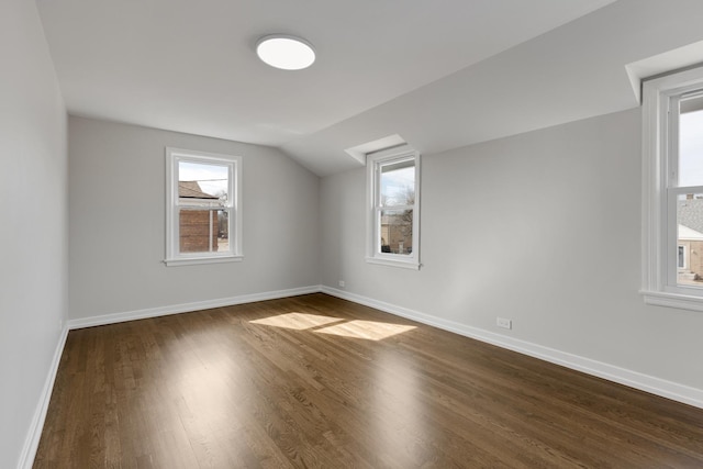 additional living space featuring dark wood-style floors, vaulted ceiling, and baseboards