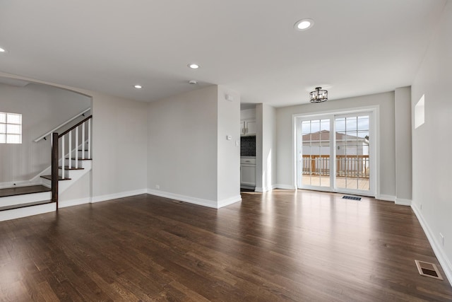 unfurnished living room featuring dark wood-style floors, visible vents, stairway, and recessed lighting